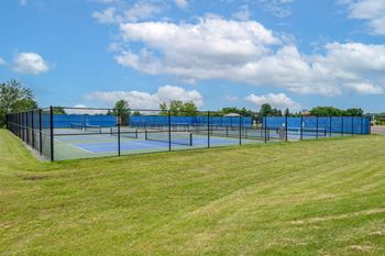 a tennis court with a fence around it on a grass field